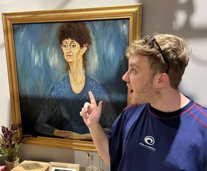 Radio Times soaps editor Michael Adams, wearing sunglasses and a blue t-shirt, stood beside the blue painting of Mrs Mangel on the set of Neighbours