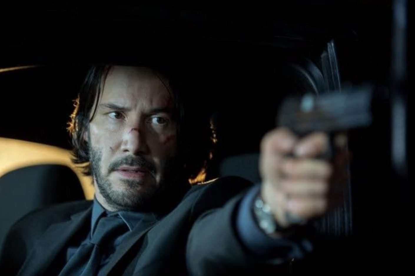 Keanu Reeves points and shoots a gun.