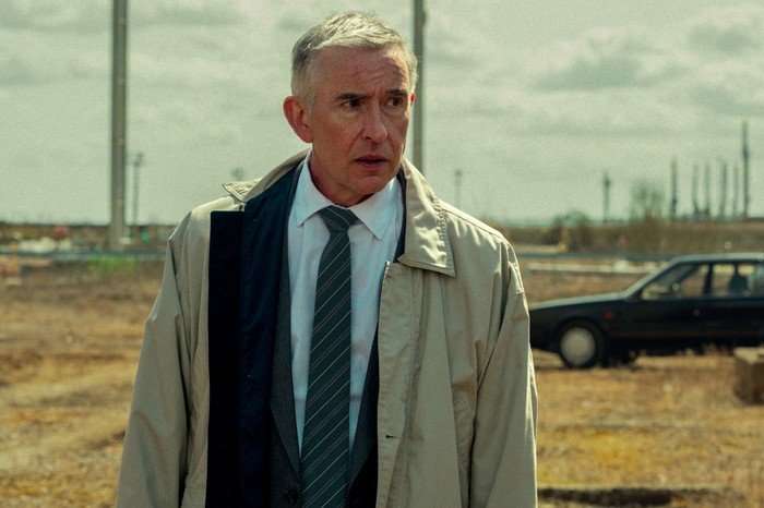 Steve Coogan as Don in Legends, wearing a suit and coat and stood outside.