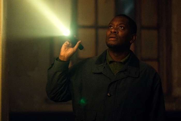 Aml Ameen as Bailey in Legends, stood in a dark room, holding up a torch.