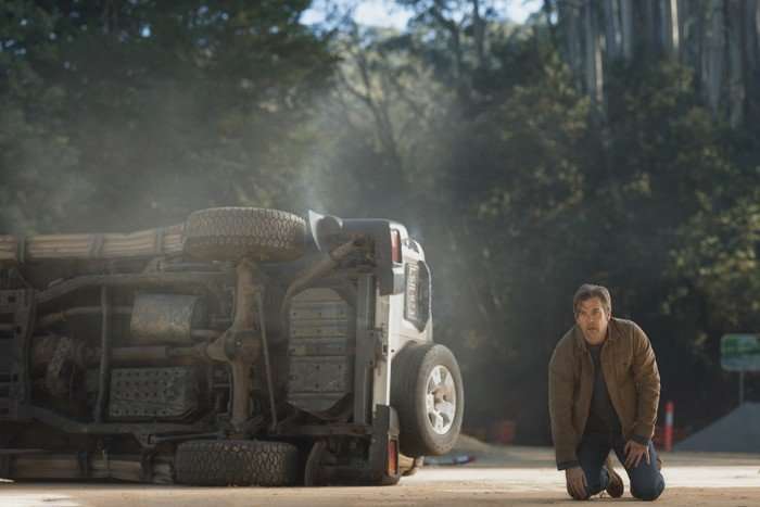 Patrick Brammall in Last Seen. A man crouching by an overturned vehicle.