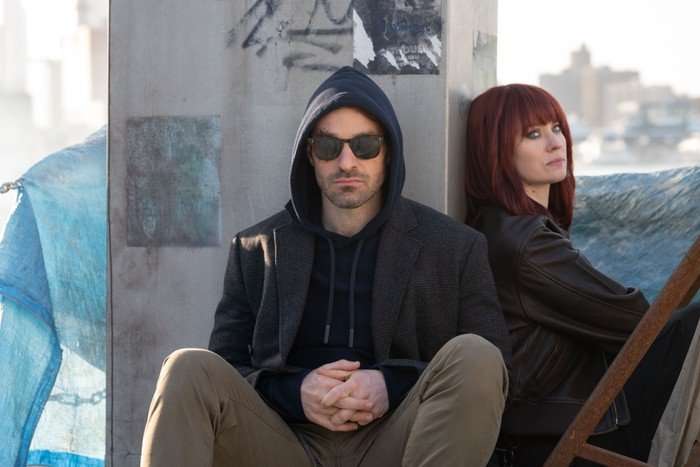 Charlie Cox as Matt Murdock and Deborah Ann Woll as Karen Page leaning against a wall in Daredevil: Born Again season 2