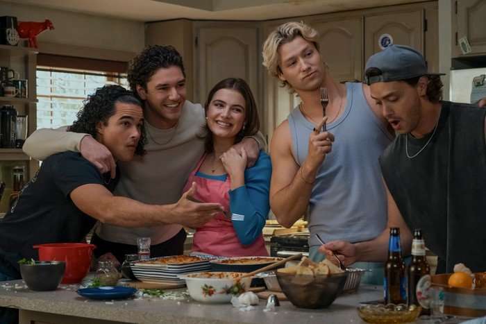 Off Campus John Tucker, Garrett Graham, Hannah Wells, Dean Di Laurentis and John Logan happily crowd around a kitchen island, with various food dishes laid out across it, in a scene from Off Campus