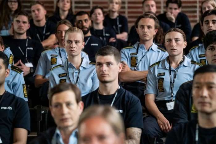 A group of trainee officers sit in on a briefing, all looking concerned