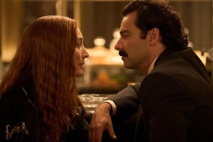Victoria Smurfit and Aidan Turner sitting closely together, looking into each other's eyes.