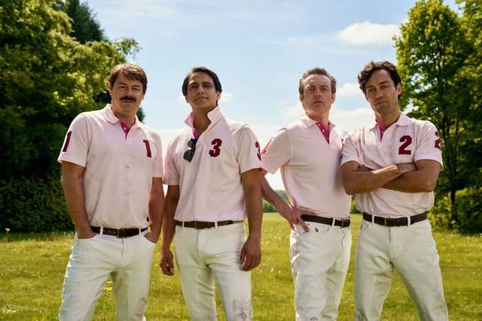 Danny Dyer as Freddie Jones, Luca Pasqualino as Bas Baddingham, Brendan Patricks as Henry Hampshire and Alex Hassell as Rupert Campbell-Black wearing pink polo shirts and standing next to one another in a field.