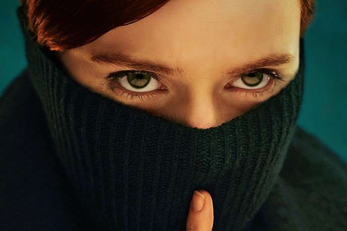 Lola Petticrew in Say Nothing, a jumper pulled up over her nose, and her finger in front of her mouth in a "shushing" motion