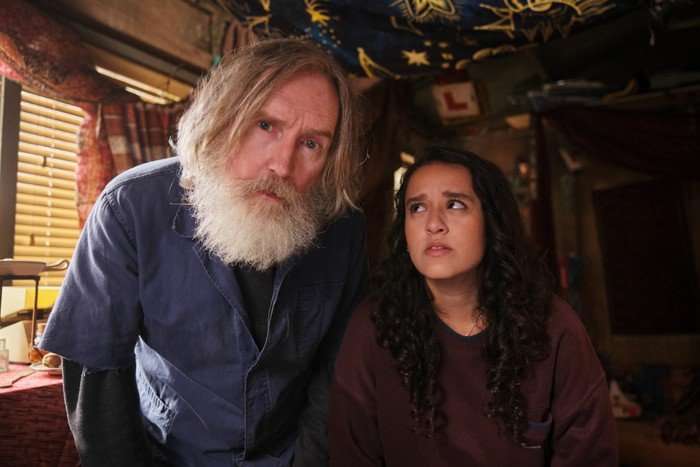 Small Prophets L-R Pearce Quigley (Michael Sleep) and Lauren Patel (Kacey). Credit - Matt Squire Pearce Quigley as Michael Sleep and Lauren Patel as Kacey in Small Prophets; Kacey is looking up at Michael in an unimpressed manner