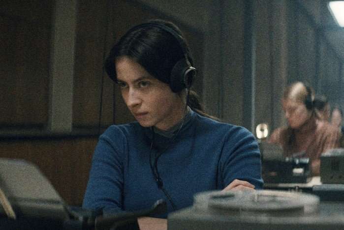 Agnes O'Casey as Irina Morozova in Star City Agnes O'Casey as Irina Morozova in Star City, sitting at a desk with headphones on, listening intently