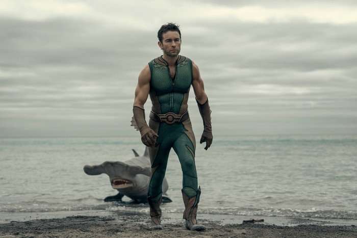 Chace Crawford as The Deep in The Boys, walking away from the sea with a shark poking out of it on the shore.