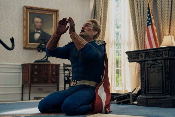 The Boys Season 5 Antony Starr as Homelander in The Boys, kneeling on the floor in the White House with his hands up and his face bloodied.