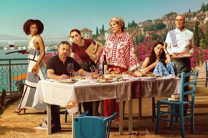 Daria (Gaia Scodellaro), DCI Joe Mottram (Warren Brown), Inspector Lara Sarrancino (Cristiana Dell'Anna), Elena Da Vinale (Phyllis Logan), Angelica (Beau Gadsdon) and Chef Gennaro (Urbano Barberini) sitting around a table with picturesque backdrop but a chair overturned in the foreground. All look worried.