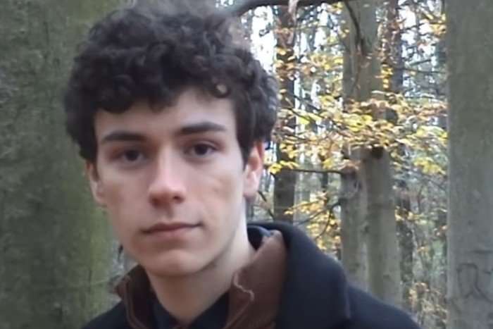 A close up of Daniel Zizka looking ahead stood in a woods.