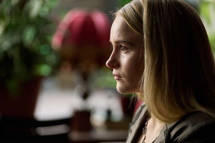 Miriam Petche as Carrie Symonds in Believe Me sitting down and facing someone with a straight face.
