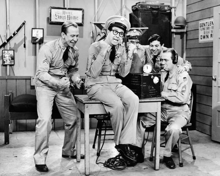 The Phil Silvers Show Sergeant Ernie Bilko, played by American comedian Phil Silvers (centre), and Corporal Steve Henshaw, played by Allan Melvin (left) celebrate good news in the US TV sitcom 'The Phil Silvers Show', circa, 1957.