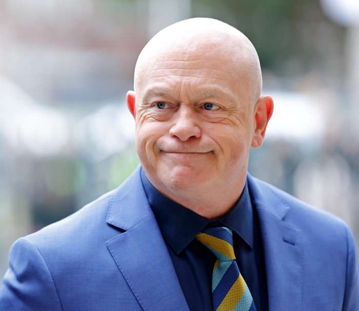 Ross Kemp smiling, wearing a blue suit with a blue and yellow striped tie.