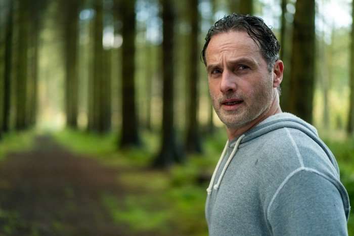 Coldwater Ep 6 Andrew Lincoln wearing a grey hoodie stood in the middle of a forest.