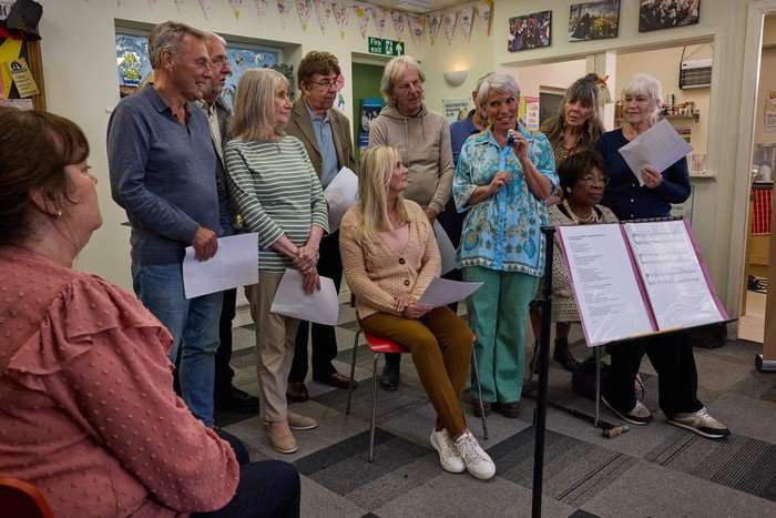 corrie-debbie-choir Debbie grins as she stands among the choir members in Coronation Street