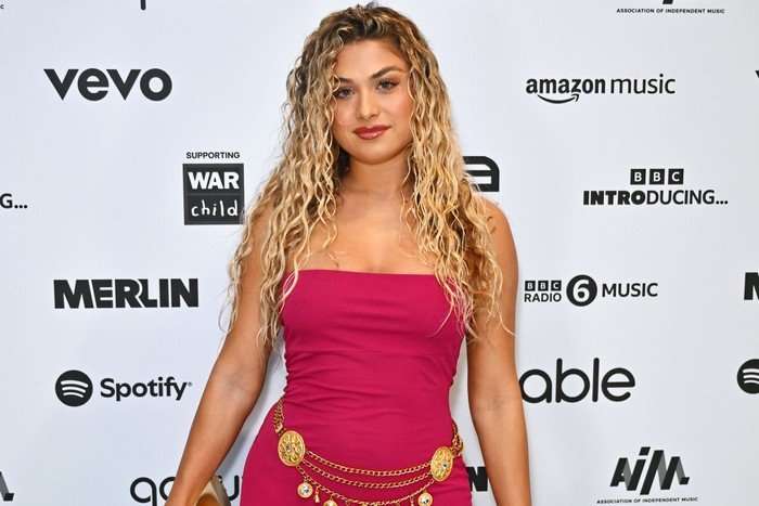 Antigoni posing on a red carpet, smiling ahead, wearing a pink dress.