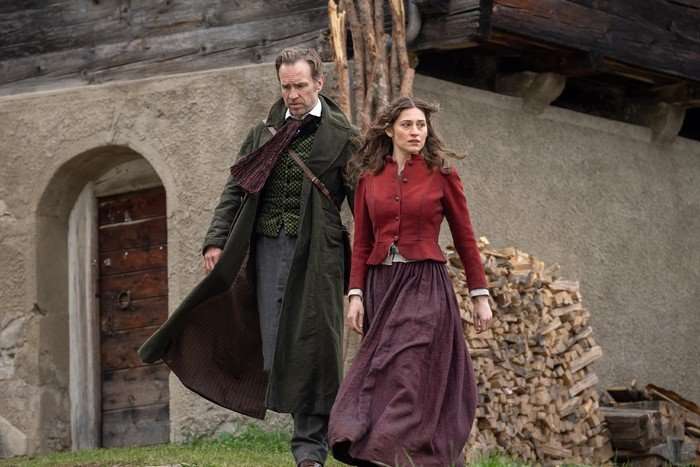 Rafe Spall and Deleila Piasko in The Death of Sherlock Holmes, walking outside a building together in period costumes.