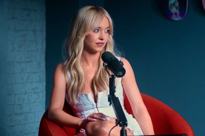 Sydney Sweeney in Euphoria season 3, sitting in a red armchair with a microphone in front of her.