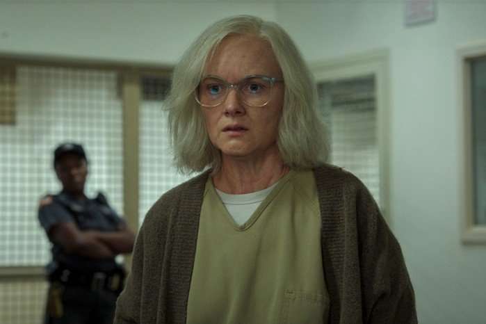 Wrenn Schmidt stars in For All Mankind season 5; in this scene, the actor has been digitally aged up to play an older version of Margo Madison. She is wearing a prison uniform and looking unhappy at something ahead of her
