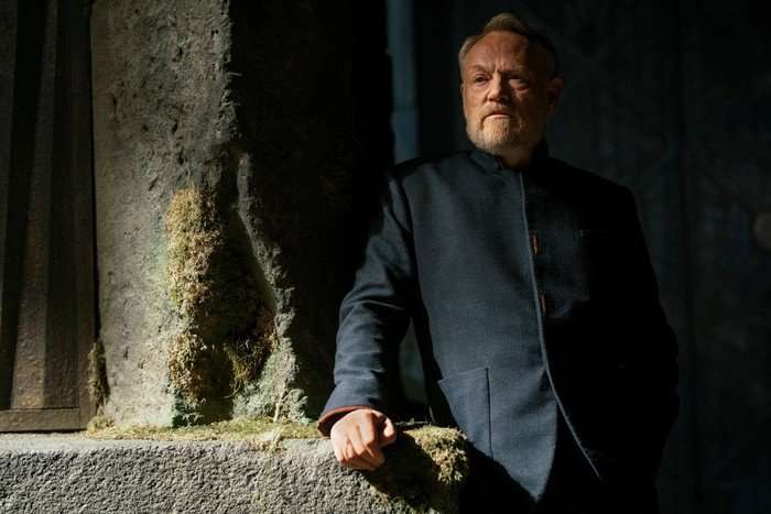 Jared Harris Jared Harris stars in Foundation season 3. His character is leaning against a stone pillar in a dark, shadowy environment