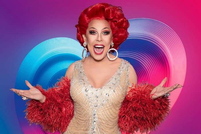 La Voix wearing a sparkly dress, smiling ahead with her hands stretched outwards.