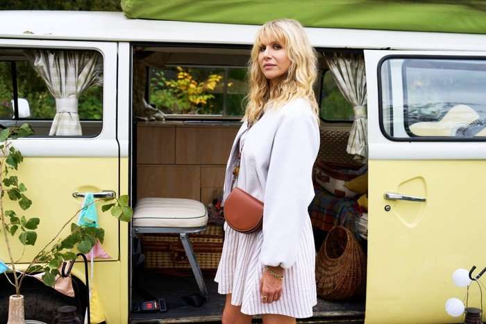 Amandaland Lucy Punch as Amanda, wearing a white dress, standing in front of a yellow campervan