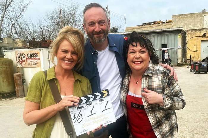 Sally Lindsay, Steve Edge and Sue Vincent stand close together, smiling on the set of The Madame Blanc Mysteries, holding a clapperboard to represent the start of filming on season 5