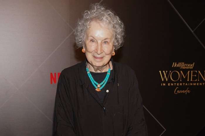 The Hollywood Reporter Women In Entertainment Canada Margaret Atwood standing at a photo call for an event, against a black backdrop and smiling.