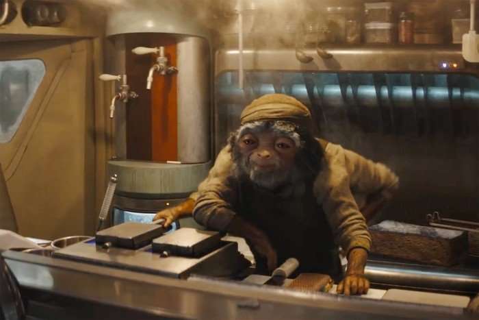 An alien cook in a food van stands behind the counter, looking out at a customer ahead of him