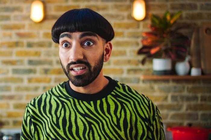 Mawaan Rizwan plays Jamma in Juice wearing a green and black striped jumper