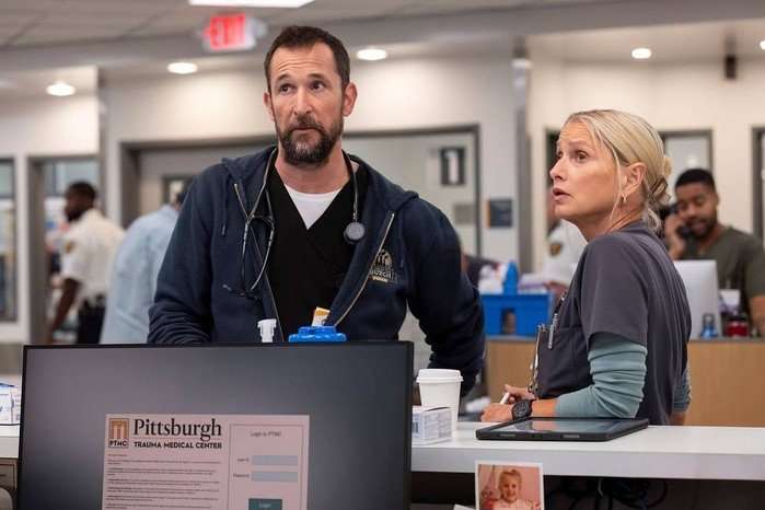noah-wyle-katherine-lanasa Noah Wyle and Katherine LaNasa in The Pitt, stood in a hospital and looking up.