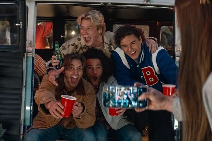 A scene from Off Campus in which frat bros Logan, Dean, Tucker, and Garrett crowd in for a party photo together, with big, excitable smiles on their faces