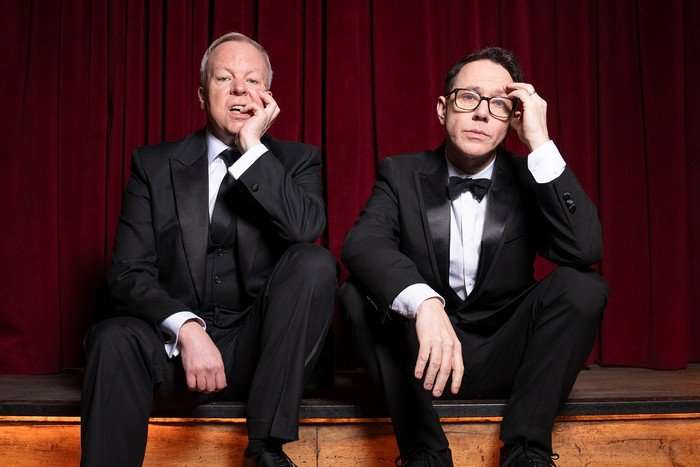 pemberton-shearsmith-inside-no-9-season-9 Steve Pemberton and Reece Shearsmith sit on the steps of a stage, with a red curtain behind them