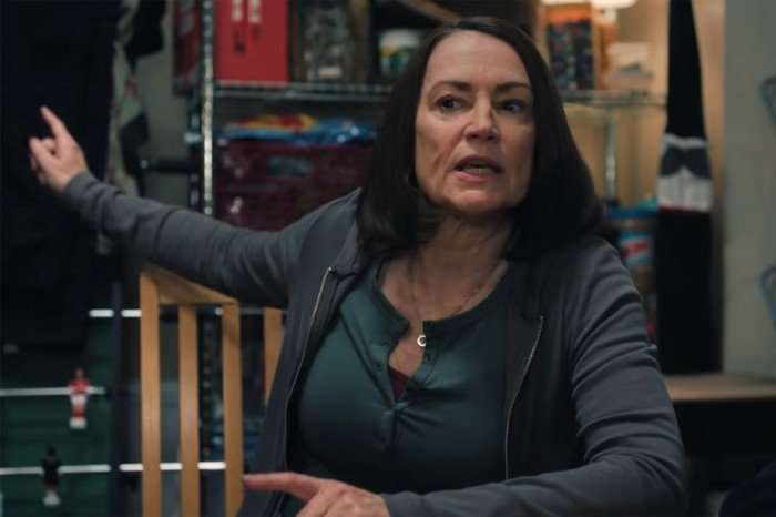 Pooky Quesnel stars in Tip Toe; in this scene, she is sat at a table, gesturing behind her as she makes a conversational point