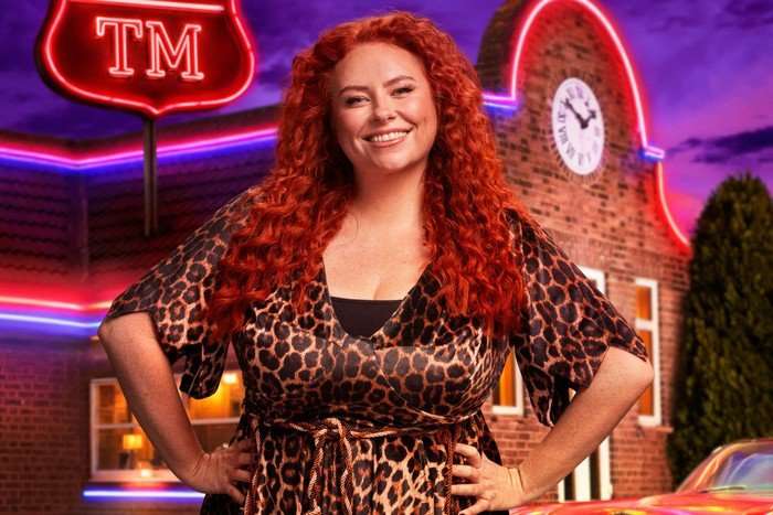 Amy Gledhill smiling and stood as she look ahead with her hands on her hips.