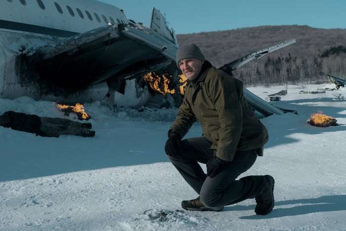 the-last-frontier-jason-clarke Jason Clarke stars in The Last Frontier; his character is kneeling down in a snowy wilderness area, with a crashed plane in the background behind him