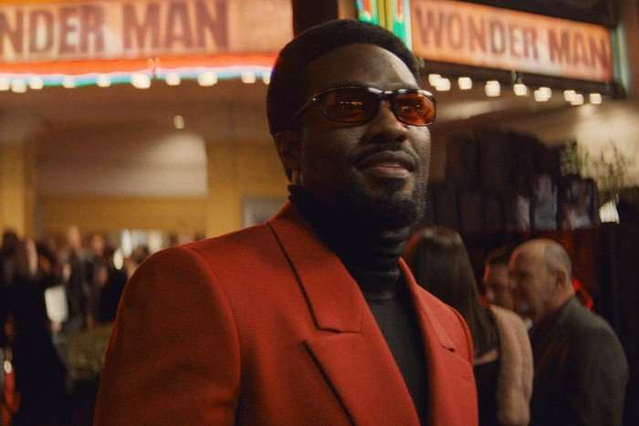 Yahya Abdul-Mateen II stars in Wonder Man; in this scene, Simon is outside a cinema, wearing a red blazer, black turtleneck and red sunglasses