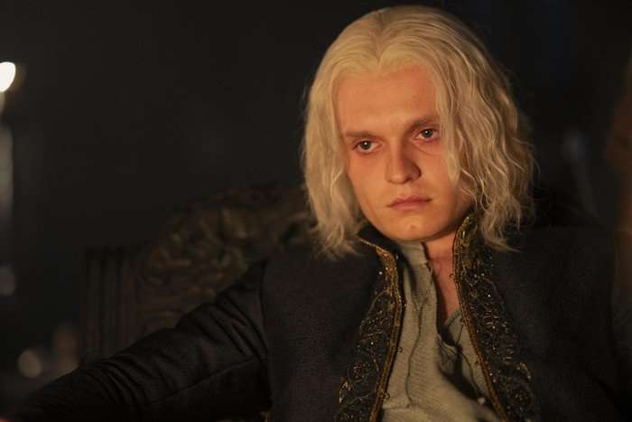 Tom Glynn-Carney sits by firelight as King Aegon II Targaryen in House of the Dragon season 2.