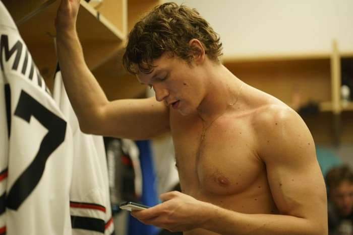 Heated Rivalry Ilya Rozanov (Connor Storrie) in Heated Rivalry; he is seen here shirtless in a sports changing room, looking at his phone as he texts someone