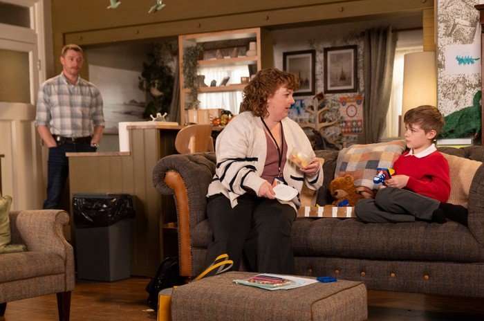 Daniel watches as a social worker, Ruth, chats to Bertie on the sofa in Coronation Street