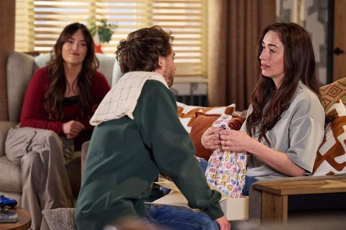Jodie watches David and Shona looking at a baby grow in Coronation Street