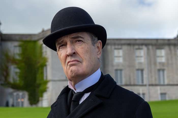 12.09.24.KS-47 Kerry Spicer Rupert Everett in period dress and a bowler hat, looking glum and standing on the lawns in front of an old stately house