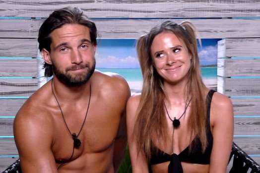 Jamie Jewitt and Camilla Thurlow Jamie Jewitt and Camilla Thurlow sat next to each other, smiling. Jamie is topless and Camilla is wearing a black bikini and they both have black microphones around their necks.