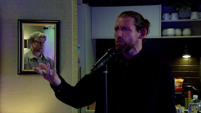 Chris Coghill as Kev Townsend, singing passionately into a microphone in Emmerdale