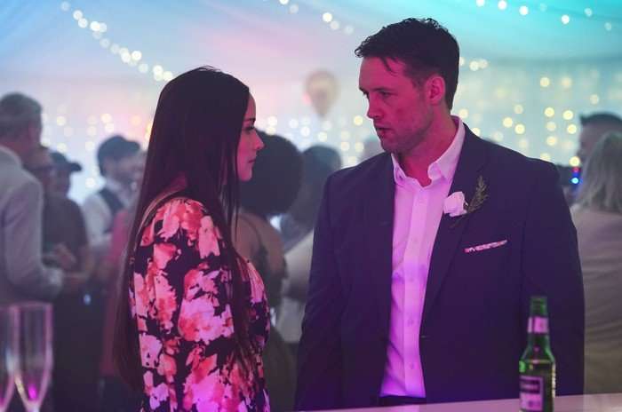 Jacqueline Jossa as Lauren Beale facing Stephen Aaron-Sipple as Mark Fowler and lit in purple in EastEnders.