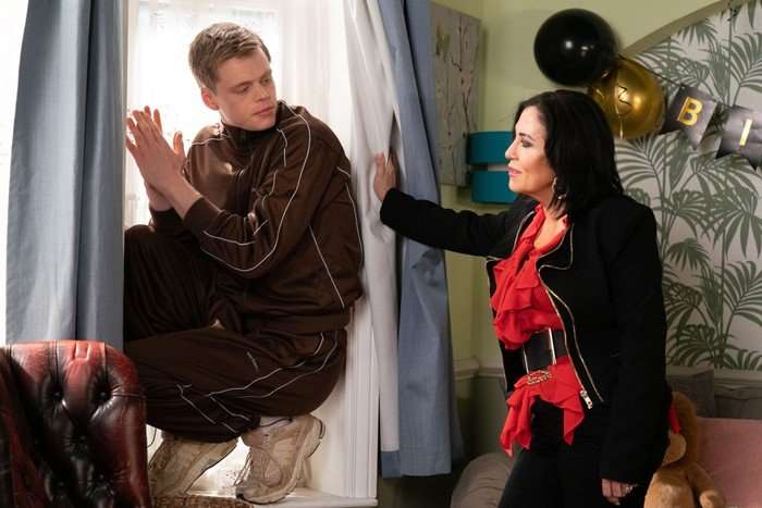 564110,TITLE:Eastenders Kat confronts a sheepish Oscar, who is hiding behind a curtain, in a scene from EastEnders