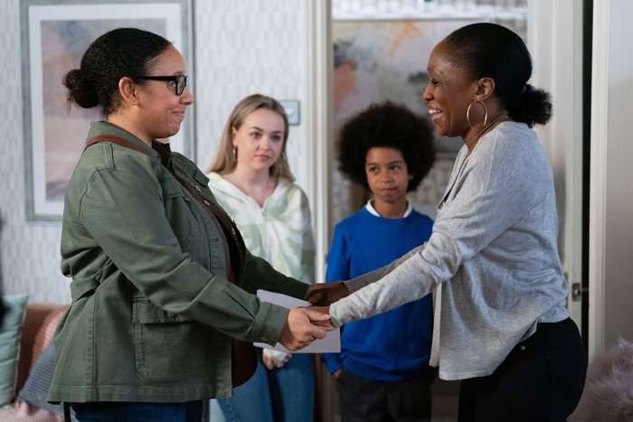 Libby holds hands with Denise, as Amy and Raymond watch on in a scene from EastEnders